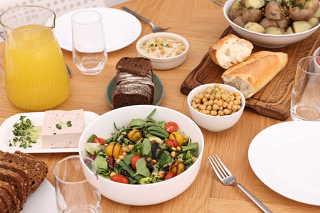 Healthy vegetarian food, glasses, cutlery and plates on wooden tableの写真素材