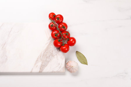 Cutting board, garlic, bay leaf and tomatoes on white marble table, flat lay. Space for textの写真素材