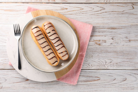 Tasty glazed eclairs served on wooden rustic table, top view. Space for text
