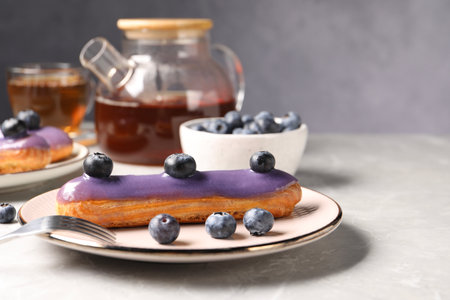 Tasty glazed eclair with blueberries on gray marble table, closeupの写真素材