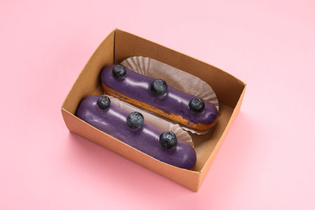 Delicious eclairs decorated with blueberries on pink backgroundの写真素材
