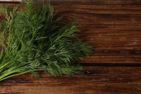 Sprigs of fresh green dill on wooden table, space for text