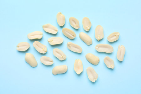 Fresh peanuts on light blue background, flat lay