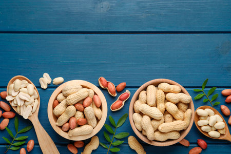 Fresh peanuts and twigs on blue wooden table, flat lay. Space for text