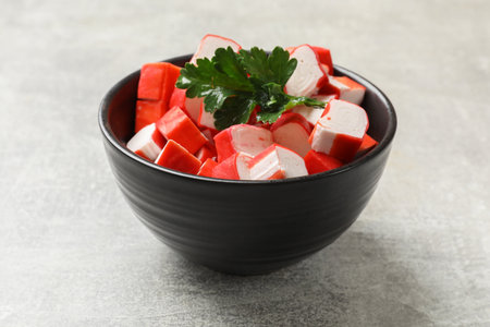 Tasty crab sticks and parsley in bowl on gray table, closeupの写真素材