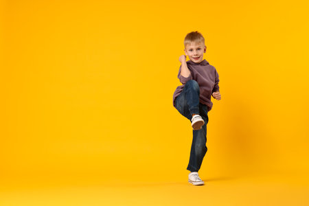 Happy little boy dancing on yellow background. Space for textの写真素材