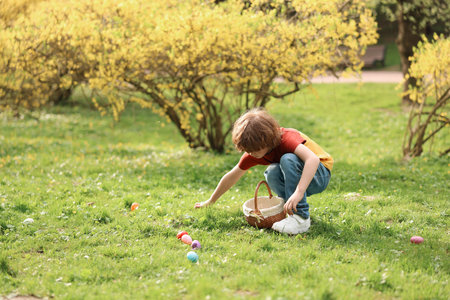 Easter celebration. Little boy hunting eggs outdoors