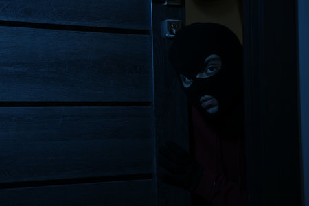 Thief in balaclava entering foreign house at night. Burglaryの写真素材