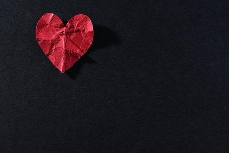 Red crumpled paper heart on black background, top view with space for text. Breakup concept