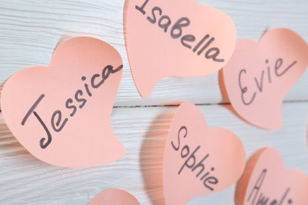Paper stickers with different names on white wooden table, closeup. Choosing baby's nameの写真素材