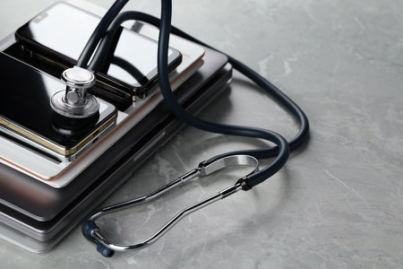 Stack of electronic devices and stethoscope on gray table, closeupの写真素材