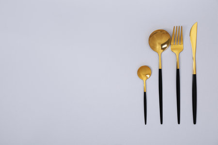 Stylish golden cutlery set on gray background, flat lay. Space for textの写真素材