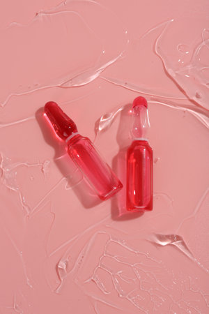 Skincare ampoules on pink surface with gel, top viewの写真素材