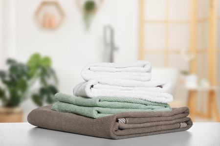 Folded fresh towels on table against blurred bathroom interiorの写真素材