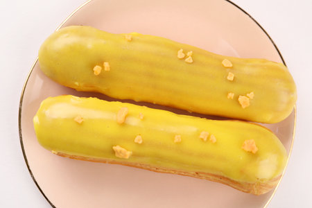 Delicious eclairs covered with glaze on white background, top view