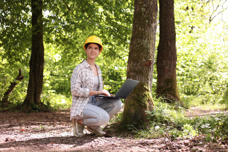 Forester in hard hat with laptop working in forestの写真素材