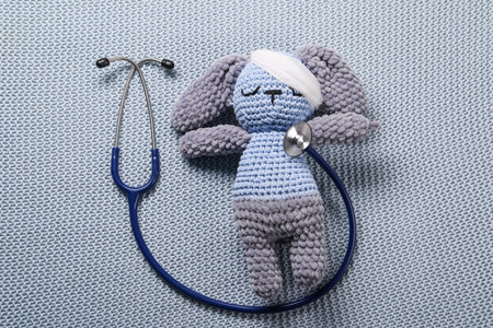 Toy bunny and stethoscope on gray blanket, top viewの写真素材