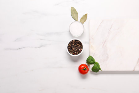 Cutting board, spices and tomato on white marble table, flat lay. Space for textの写真素材