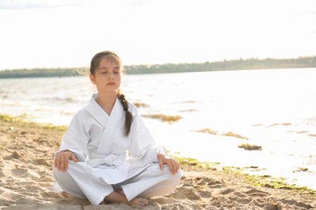 Cute little girl in kimono meditating near river. Karate practicingの写真素材