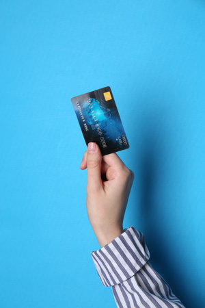 Woman holding credit card on light blue background, closeupの写真素材