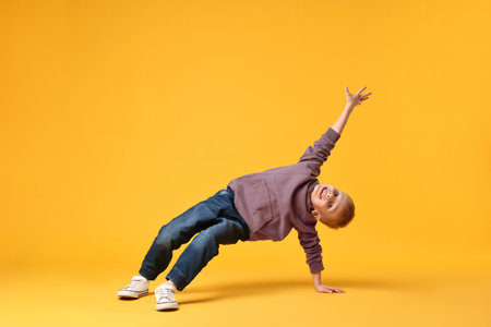 Happy little boy dancing on yellow backgroundの写真素材
