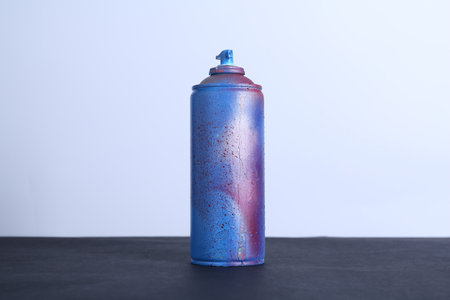 Spray paint can on black surface against white backgroundの写真素材