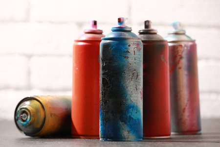 Many spray paint cans on gray surface against white brick wall, closeupの写真素材