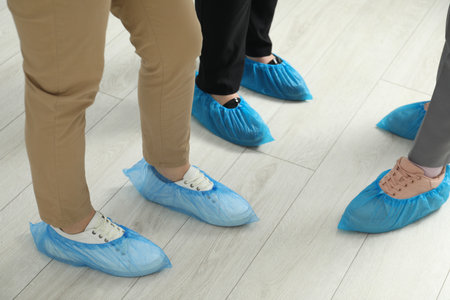 Women wearing blue shoe covers onto different footwear indoors, closeupの写真素材