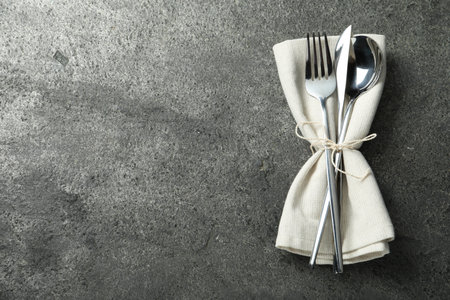 Stylish silver cutlery and napkin on gray table, top view. Space for textの写真素材