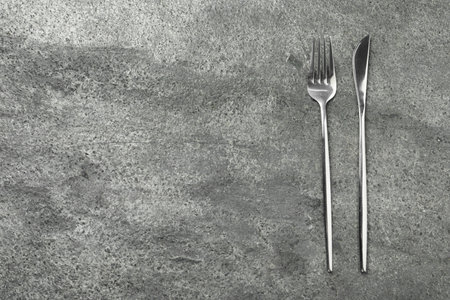 Stylish silver cutlery on gray table, top view. Space for textの写真素材