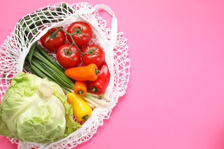 String bag with different vegetables on bright pink background, top view. Space for textの写真素材