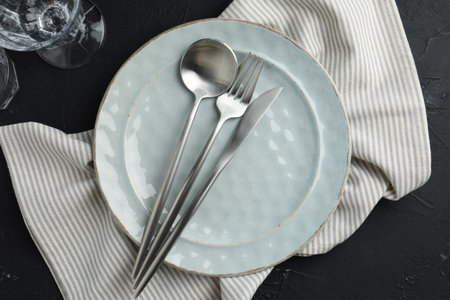 Stylish setting with cutlery, napkin and plate on dark table, flat lay