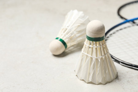 Feather badminton shuttlecocks and rackets on gray background, closeup. Space for text