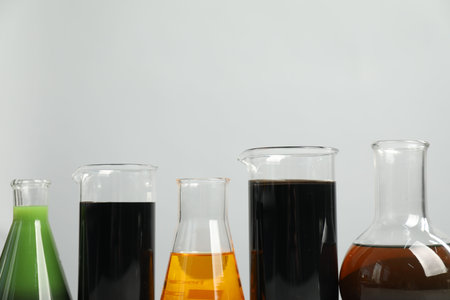 Laboratory glassware with different types of oil on white background, closeup. Space for text