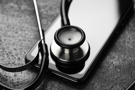 Modern smartphone and stethoscope on gray table, closeupの写真素材