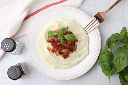 Fried bacon, mashed potato, basil and fork on white tiled table, top viewの写真素材
