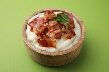 Fried bacon, mashed potato and parsley in bowl on green backgroundの写真素材