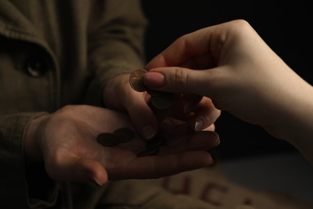 Woman giving coins to homeless, closeup. Charity and donationの写真素材