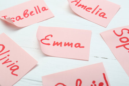 Paper stickers with different names on white wooden table, closeup. Choosing baby's nameの写真素材