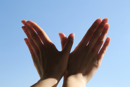 Woman making hand gesture like bird on light blue background, closeup