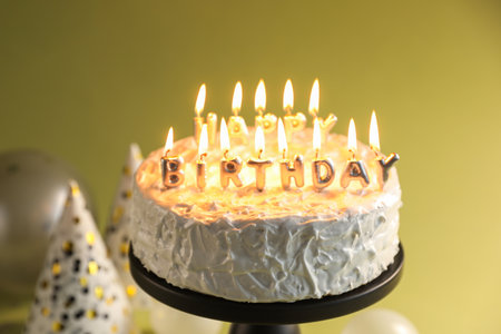 Tasty birthday cake with burning candles on green background, closeupの写真素材