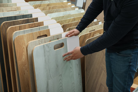 Man choosing wooden flooring among different samples in shop, closeupの写真素材