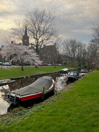 Picturesque view of canal with moored boats and blossoming trees in springのeditorial素材