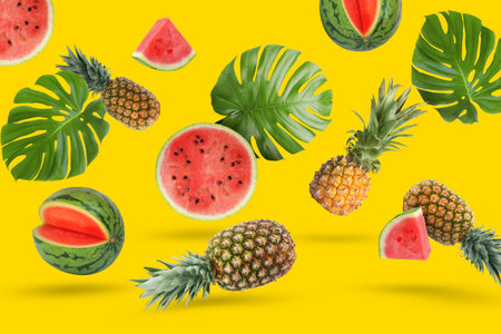 Summer party. Tropical fruits and leaves in air on yellow backgroundの写真素材