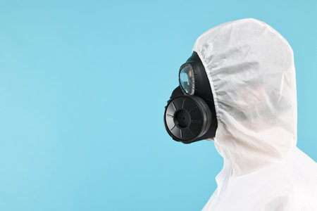 Worker in gas mask on light blue background. Space for textの写真素材