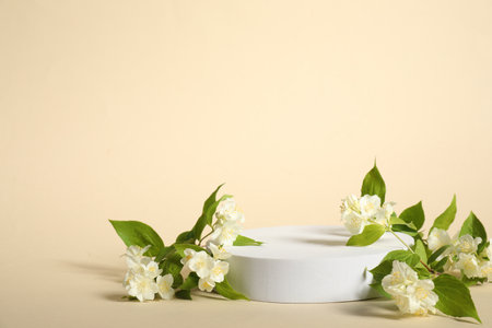 Presentation of product. White podium and beautiful jasmine flowers on beige background, space for textの写真素材