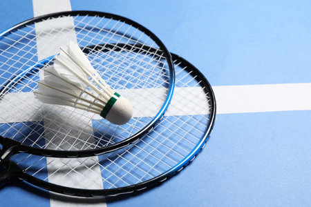 Feather badminton shuttlecock and rackets on blue background, closeup. Space for textの写真素材