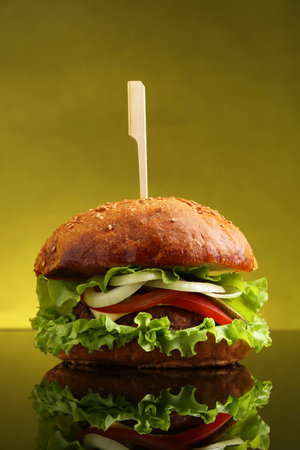 Delicious vegetarian burger on mirror surface against olive backgroundの写真素材