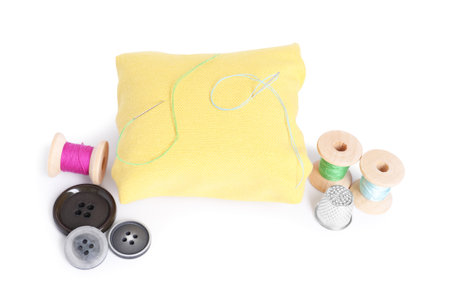 Pincushion, sewing needles, spools of threads, buttons and thimble isolated on white
