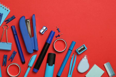 Flat lay composition with stapler and different stationery on red background, space for textの写真素材